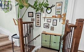 Ottawa condo for rent - A staircase with a wooden banister and a green cabinet under a shelf with pictures on the wall.
