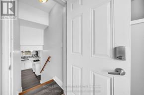 Ottawa apartment for rent - A white door with a silver handle is in the foreground of a photo showing a hallway.