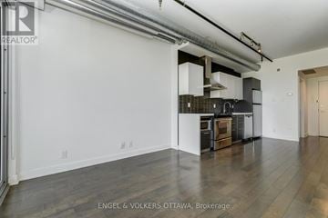 Ottawa condo for rent - A modern kitchen with white cabinets and a black stove top oven.