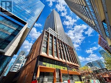 Toronto (Waterfront Communities) condo for rent - A tall building with a pointed top is surrounded by other buildings.