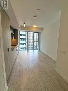 Toronto (Waterfront Communities) condo for rent - A long hallway with wood floors and a sliding glass door.
