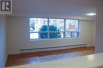 Toronto (Englemount-Lawrence) multi-family for rent - A room with a window showing a view of a building and trees outside.