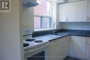 Toronto (Englemount-Lawrence) multi-family for rent - A kitchen with white cabinets and a black countertop.