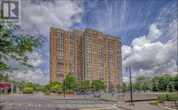 Toronto (Steeles) condo for rent - A large apartment building with a parking lot in front.