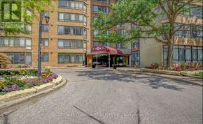 Toronto (Steeles) condo for rent - A building with a red awning is in the middle of a paved courtyard.