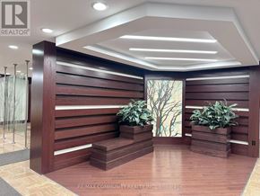 Toronto (Steeles) condo for rent - A wooden reception desk with a glass partition and a tree painting on the wall.