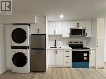 Bradford West Gwillimbury (Bradford) apartment for rent - A white kitchen with a washer and dryer on the left and a dishwasher and oven on the right.