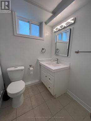 Bradford West Gwillimbury (Bradford) apartment for rent - A white bathroom with a toilet, sink, and mirror.