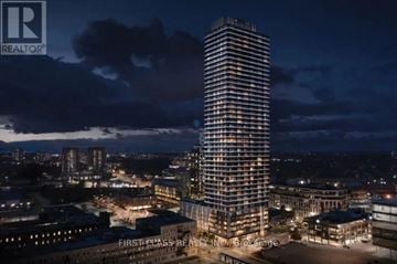 Kitchener condo for rent - A tall building with many windows is lit up at night.