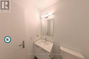 Kitchener condo for rent - A white sink in a bathroom with a mirror and a light above it.