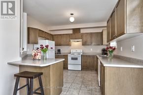 Brampton (Bram West) apartment for rent - A kitchen with a white stove and wooden cabinets.