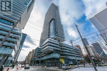Toronto (Mount Pleasant West) condo for rent - A tall building with a curved glass facade stands in front of other buildings.