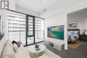 Toronto (Mount Pleasant West) condo for rent - A modern living room with a large flat screen TV and a balcony with a view of the city.
