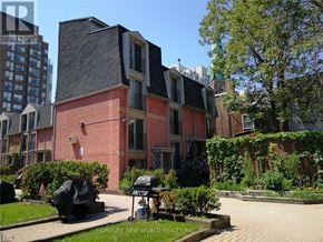 Toronto (Moss Park) townhouse for rent - A brick house with a black roof and a garden in front.