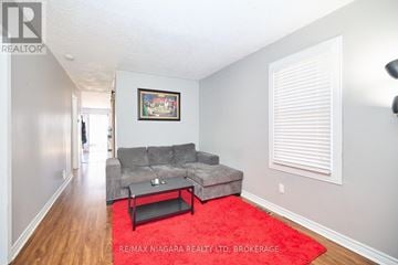 St. Catharines (Western Hill) apartment for rent - A living room with a grey couch and a red rug.