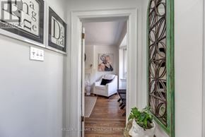 Toronto (The Beaches) apartment for rent - A woman is standing in a hallway with a white couch and a green abstract painting on the wall.