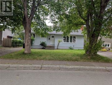 St. John's multi-family for rent - A house with a white door and windows is surrounded by trees.