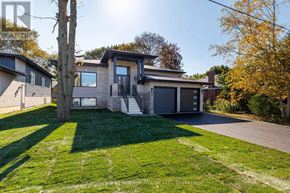 Port Colborne (Sugarloaf) apartment for rent - A modern house with a grey exterior and a black door is surrounded by a green lawn and trees.