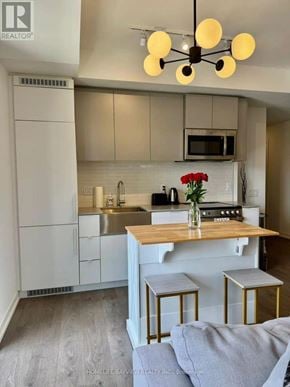 Toronto (South Parkdale) condo for rent - A kitchen with a white fridge, a wooden island, and a microwave above the stove.