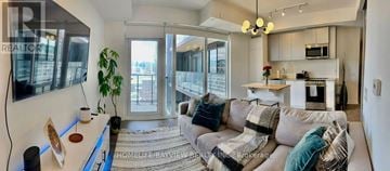 Toronto (South Parkdale) condo for rent - A modern living room with a grey couch and a large window.