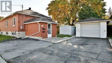 Oshawa (Central) apartment for rent - A red brick house with a white garage door is for sale.