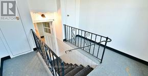 Oshawa (Central) apartment for rent - A staircase with a metal railing and a tiled floor.