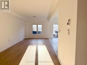 Barrie apartment for rent - A spacious room with wooden floors and white walls.
