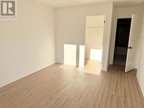 Barrie apartment for rent - A room with wooden flooring and white walls, with a door open to a dark space.