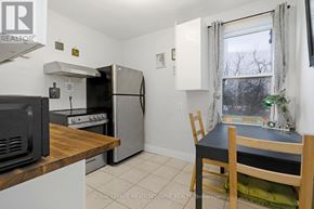 Toronto (Dovercourt-Wallace Emerson-Junction) townhouse for rent - A kitchen with a refrigerator, microwave, oven, and a table with a plant on it.