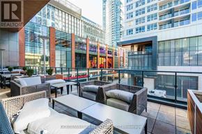 Toronto (Waterfront Communities) condo for rent - A rooftop patio with tables and chairs overlooking a cityscape.