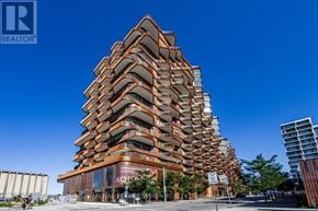 Toronto (Waterfront Communities) condo for rent - A tall building with a brown facade and balconies is the main focus of the image.