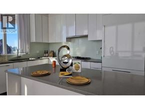 Burnaby apartment for rent - A kitchen with white cabinets and a countertop with plates and a sign.