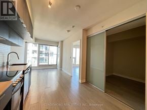 Toronto (Moss Park) condo for rent - A kitchen with a stove top oven and a sliding glass door leading to a balcony.