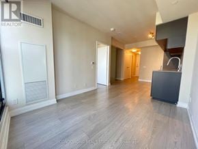 Toronto (Moss Park) condo for rent - A spacious room with wood flooring and a kitchen island in the corner.