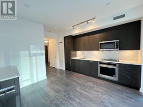 Toronto (Waterfront Communities) condo for rent - A modern kitchen with dark wood cabinets and stainless steel appliances.