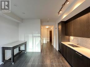 Toronto (Waterfront Communities) condo for rent - A modern kitchen with dark wood floors and a white countertop.