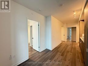 Vaughan (Vaughan Corporate Centre) condo for rent - A room with white walls and wooden flooring with a door in the middle.