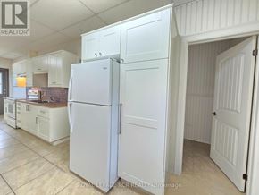 East Gwillimbury apartment for rent - A white refrigerator stands in a kitchen with white cabinets.