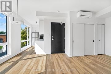 Ottawa multi-family for rent - A spacious room with wooden flooring and white walls, featuring a black door and a kitchen area with white appliances.
