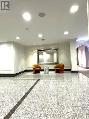 Toronto (Newtonbrook East) condo for rent - A hallway with a mirror, two chairs and a trash can.