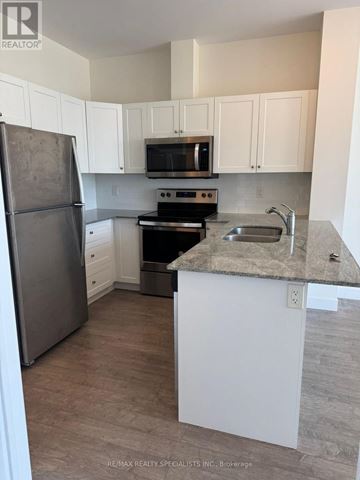 Kitchener condo for rent - A kitchen with white cabinets and a granite countertop.