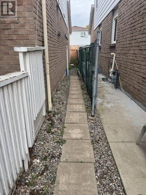 Brampton (Fletcher's West) apartment for rent - A narrow alley with a concrete path and a metal fence on the right side.