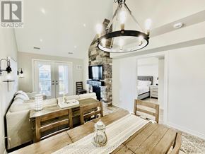 Collingwood condo for rent - A well-lit, modern living room with a stone fireplace and a wooden dining table.