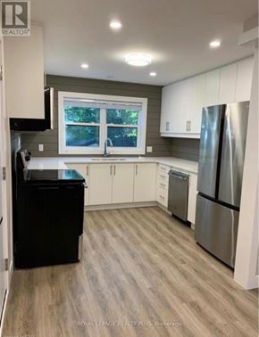 Kitchener multi-family for rent - A kitchen with a black trash can and a window.