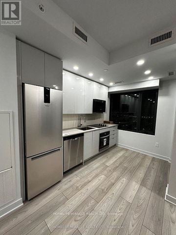 Vaughan (Vaughan Corporate Centre) condo for rent - A modern kitchen with stainless steel appliances and wooden flooring.