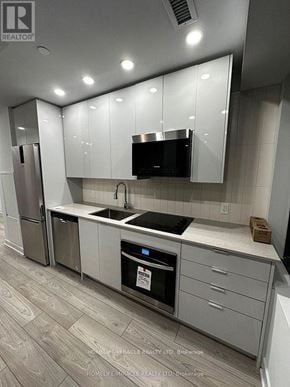 Vaughan (Vaughan Corporate Centre) condo for rent - A modern kitchen with a stainless steel refrigerator, a black microwave, and a stainless steel oven.