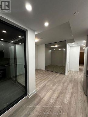 Vaughan (Vaughan Corporate Centre) condo for rent - A spacious room with wooden flooring and a large mirror on the wall.