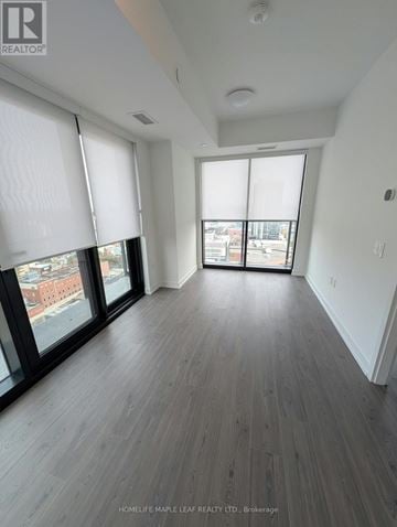 Kitchener condo for rent - A spacious room with wooden flooring and large windows.