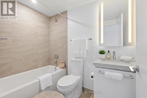 Toronto (Leaside) condo for rent - A white toilet sits in a bathroom with a white tub and sink.