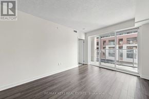 Toronto (Humber Heights) condo for rent - A spacious room with wooden flooring and a view of a building through the glass door.